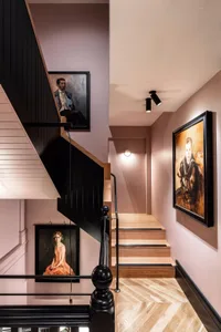 Modern staircase featuring black railings, wooden steps, and framed artworks on the walls.
