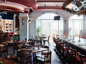 以磚牆與混凝土打造的餐廳室內，陳設餐桌、餐椅及吧台。