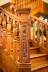 A detailed wooden staircase with intricate carvings and a decorative column.