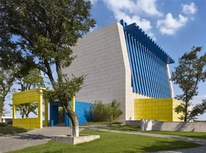 A modern building with a glass facade, yellow accents, and a white exterior.