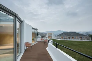 現代陽台區域，木質地板、戶外座椅，以及住宅大樓與山景的視野。