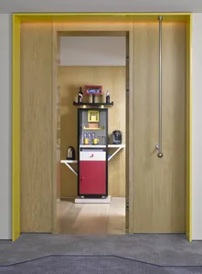 Modern coffee bar featuring wooden shelves and cabinets, with a variety of coffee-making equipment and snacks.
