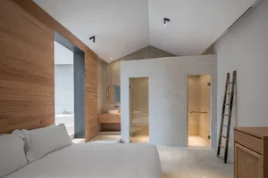 A minimalist bedroom featuring concrete walls and a clean, uncluttered design.