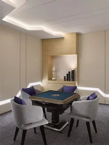 A modern minimalist gaming room with fabric chairs, a wooden table, and glass accents.