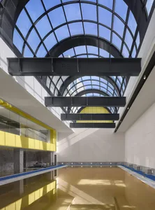 Modern glass indoor pool with a glass ceiling and minimalist design.