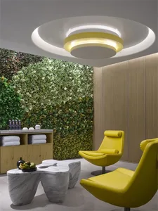 A modern living space featuring a vertical garden, marble table, yellow chairs, and wooden walls.