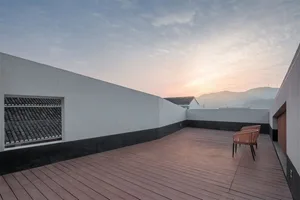 Modern rooftop terrace with wooden tiles and a view of distant mountains and sunset.