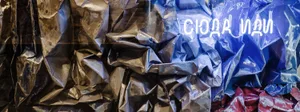 A crumpled sheet of wrinkled paper with varying shades of blue and brown. The texture and lighting create a dramatic, abstrac