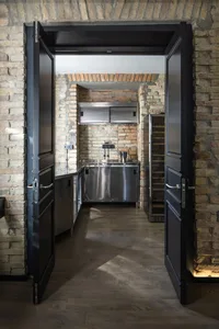 Industrial-style kitchen with brick walls, steel cabinets, and wooden flooring.