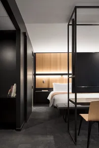 Modern minimalist bedroom with black and white color scheme, wooden accents, and steel furniture.