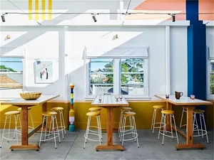 Modern café interior with wooden tables, concrete floor, and metal stools