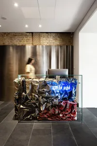 A modern front desk made of textured paper with colorful paper crumpled into the glass cubicle.