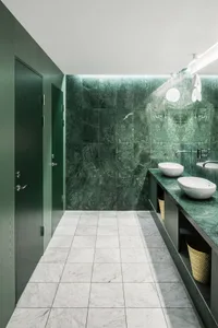 A modern bathroom with green marble walls and white sinks.