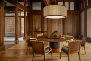 Modern dining room with wooden furniture and a bonsai tree centerpiece.