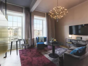 Modern living room with textured fabric furniture, large windows, and a chandelier.