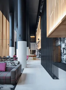 Modern lobby interior with concrete columns, wooden paneling, and contemporary furniture.