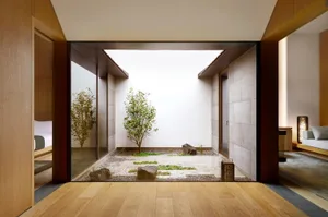 A modern minimalist living room featuring a glass door and wooden floor, showcasing the integration of indoor and outdoor spa