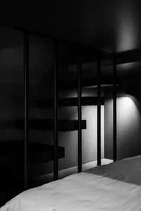 A modern minimalist bedroom with metal shelving and a white bed.