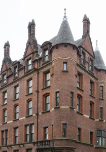A brick building with intricate architectural details, featuring conical roof structures and large windows.