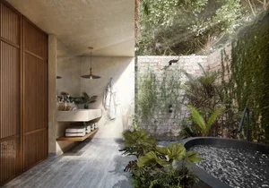 Industrial-style bathroom with concrete walls, garden tub, and tropical plants.