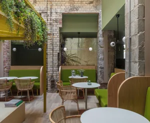 A modern, industrial-style coffee house interior with wooden furniture and green accents.
