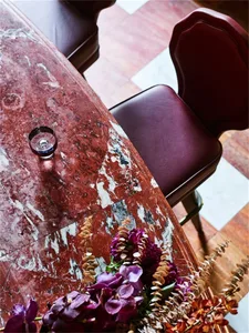 Industrial restaurant interior with dark-red marble countertop and purple flowers.