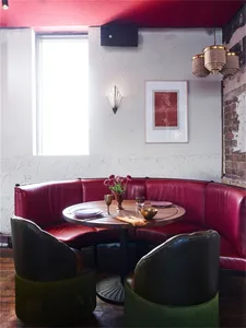 Circular seating area with red leather booths and wooden table in an industrial-style restaurant interior