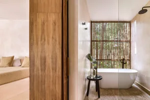 A minimalist bathroom featuring a freestanding bathtub, a wooden screen, and natural materials.