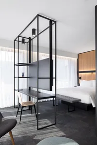 Modern bedroom featuring a minimalist design with black metal frame, glass, and fabric elements.