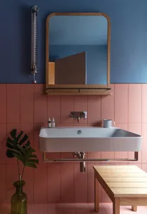Modern bathroom with ceramic tiles, a floating white sink, and a wooden mirror frame.