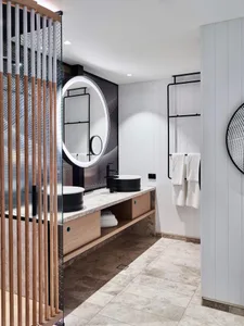 Modern bathroom featuring marble countertops, wooden cabinets, and metal hardware.