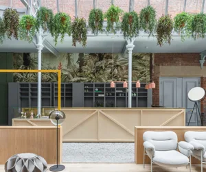 Modern commercial space featuring industrial design elements such as exposed concrete, wooden furnishings, and hanging green 