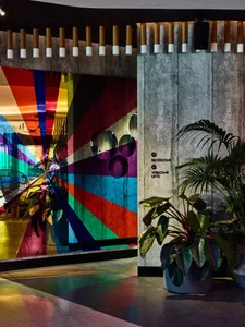 A modern hotel lobby featuring a colorful geometric installation on a concrete wall.