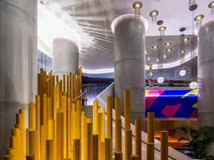 A modern hotel lobby featuring concrete and wood materials, with industrial lighting fixtures.