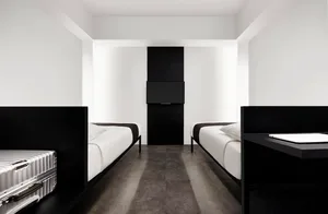Modern hotel room with two single beds, white bedding, metallic black headboards, and a television mounted on the wall in a m