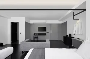 Modern minimalist hotel room featuring a concrete floor and furniture, with a television mounted on the wall and a stylish wh