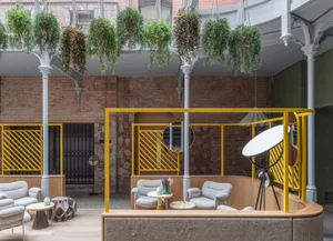 Modern coffee shop featuring industrial design elements, concrete floors, wooden furniture, and green plants.