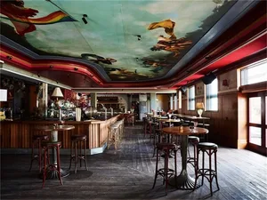 An empty restaurant interior with wooden ceiling and metal stools