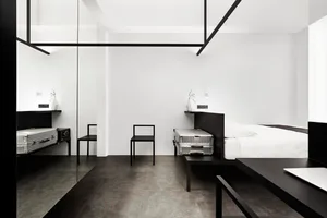 Modern minimalist bedroom featuring black and white decor with metallic luggage and furniture.