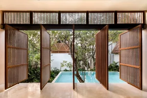 An open wooden gate, revealing a serene pool and lush greenery.