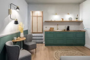 A modern industrial residential kitchen with green cabinets, wooden countertops, and a concrete floor.