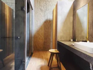 A minimalist bathroom with concrete walls, wooden accents, and glass shower enclosure.