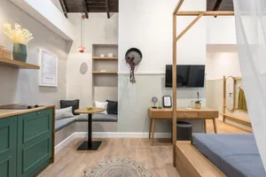 Minimalist living room with wood furniture, grey couch, and round rug.