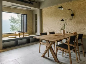 Modern dining room featuring a wooden table and chairs, with a view of mountains outside through a window.