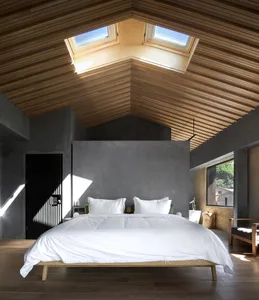 Modern minimalist bedroom featuring a wooden floor, white bedding, and large windows with skylights.