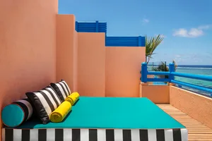 A modern residential design featuring a deck with blue and black striped textiles and yellow towels, set against a peach-colo