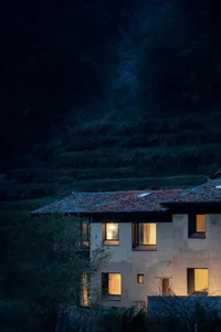 A rustic house with concrete walls and tiled roof in the evening