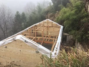 A construction site with a wooden frame structure covered in white plastic sheeting