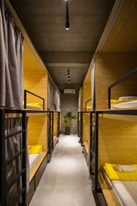 A long row of bunk beds arranged in a corridor with wooden walls and metal railings, featuring curtains for privacy.