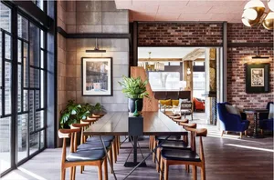 Industrial-style restaurant interior with brick walls, concrete flooring, and wooden furniture.